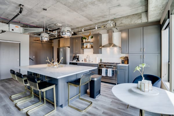 Modern kitchen with gray cabinets, marble island, and industrial ceiling design.