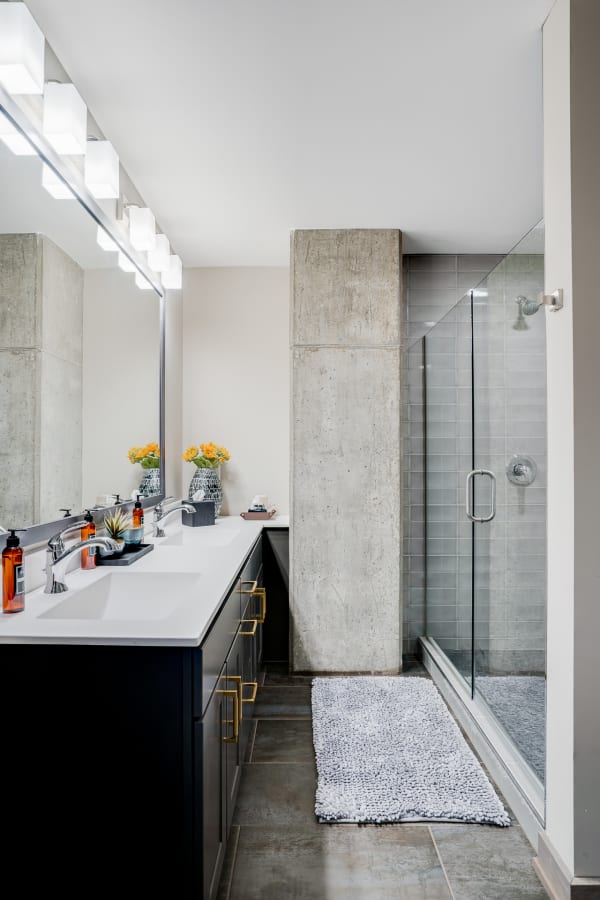 A modern bathroom with a stylish sink area, glass shower, and bright yellow flowers.