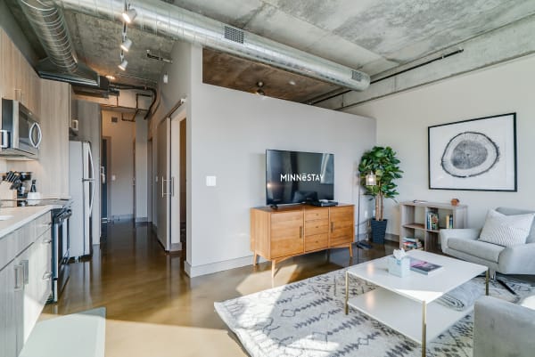 A stylish living room featuring a kitchen, sofa, coffee table, and decorative elements.