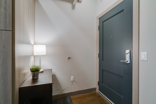 An entrance hallway with a dark blue front door, a console table, and a lamp.