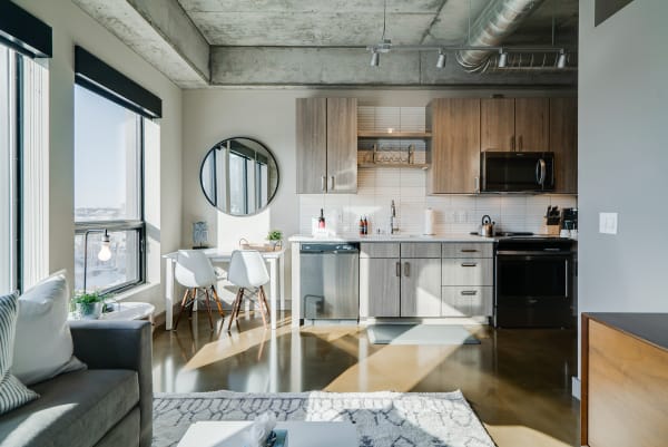 A modern kitchen and living area with a sofa, dining table, and large windows.