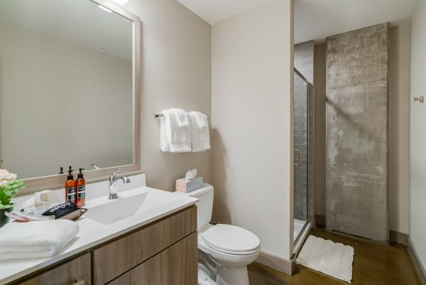 Contemporary bathroom with a white sink, wooden vanity, and glass shower.