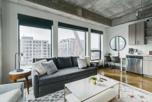 Modern apartment living area with a grey sofa and large windows.