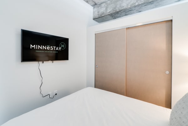 Minimalist bedroom with a mounted TV and sliding closet doors.