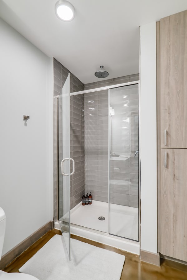 A sleek, modern shower with gray tiles, glass enclosure, and toiletries arranged inside.