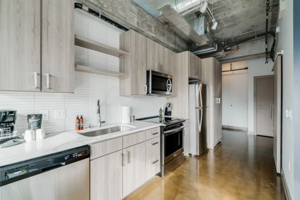 Modern kitchen with wooden cabinets, stainless steel appliances, and polished concrete floor.