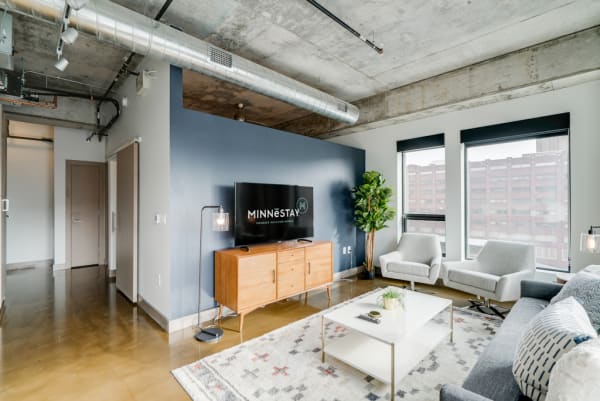 Interior view of a stylish living room featuring a blue accent wall, polished concrete floor, and modern furniture.