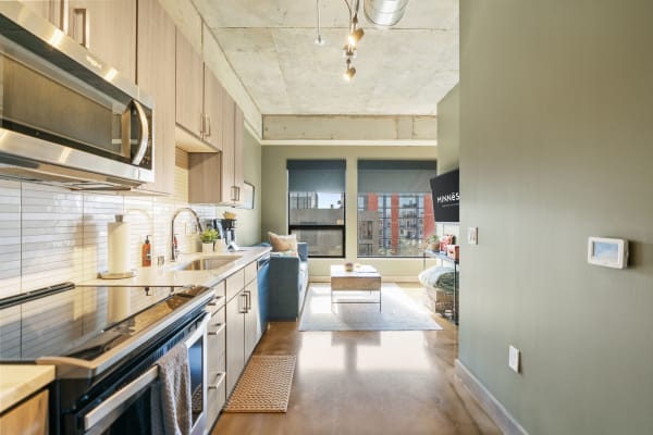 A modern kitchen and living area in an apartment with light wood cabinets and urban views.