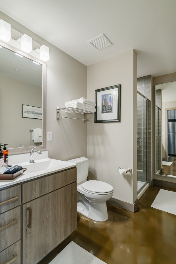 A stylish bathroom with a wooden vanity, white countertop, and a glass shower.