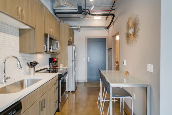 Modern kitchen and dining area showcasing light wood cabinets, stainless steel appliances, and a glass dining table.