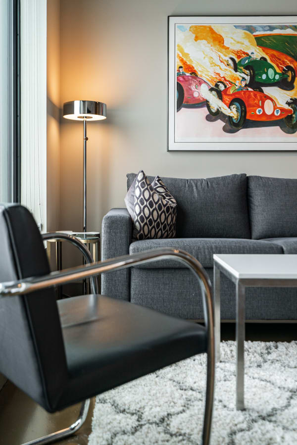 Modern living room with a grey sofa, black chair, and colorful racing art on the wall.