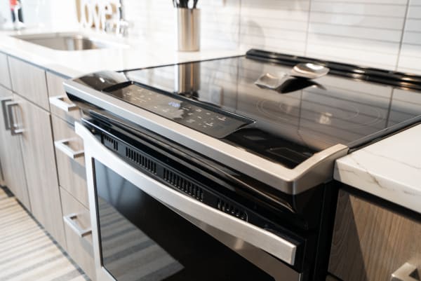Contemporary electric range with a glossy black surface and stainless steel finishes in a kitchen.