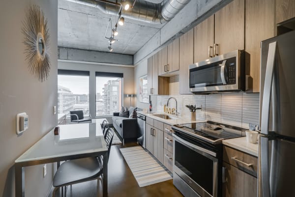 Modern kitchen with wooden cabinets, sleek appliances, and a dining table in a stylish apartment.