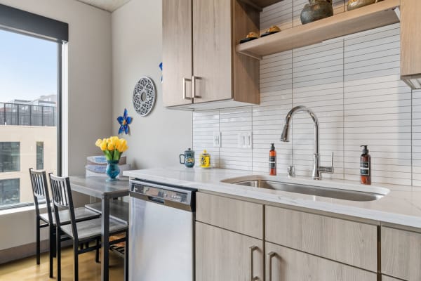 Modern kitchen with yellow tulips on the table and stainless steel appliances.
