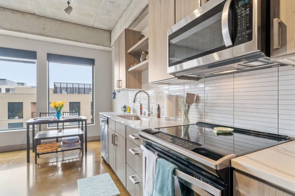 Modern kitchen with wood cabinetry, stainless steel appliances, and a dining table with yellow tulips.