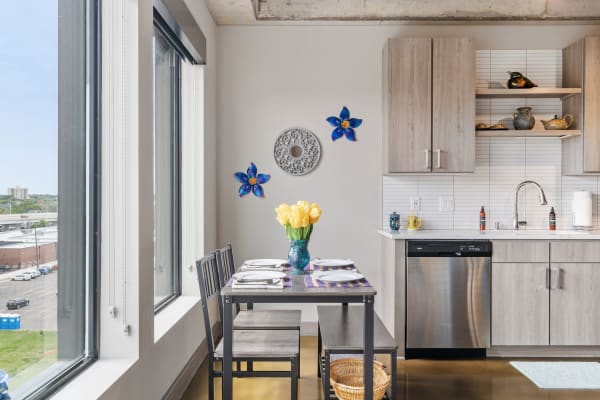 A modern kitchen nook with a dining table, yellow tulips, and blue flower wall decorations.