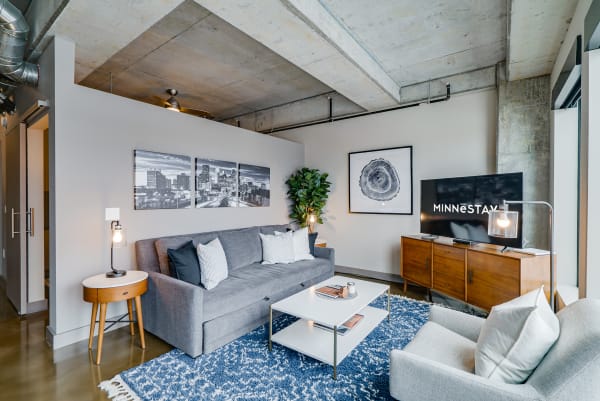 A modern living room with gray sofa, decorative pillows, and city skyline artwork.