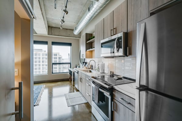 A sleek kitchen with stainless steel appliances and large city-view windows.