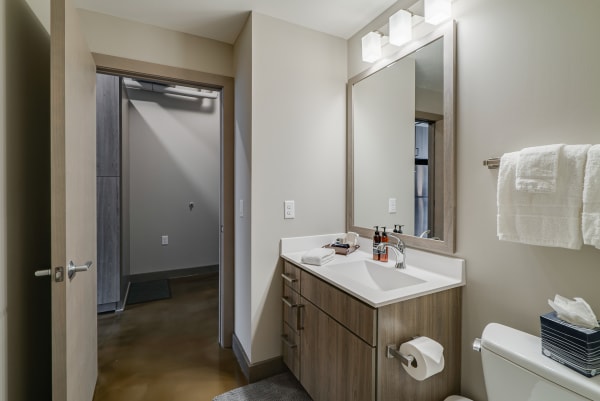 A modern bathroom featuring a white sink, wooden vanity, and large mirror.