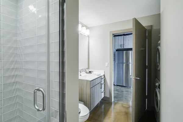 Interior view of a modern bathroom connected to a kitchen and laundry area.