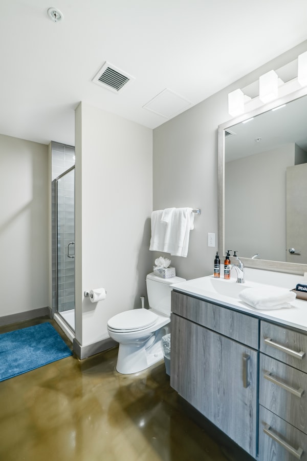 A contemporary bathroom with a glass shower, wood vanity, and modern fixtures.