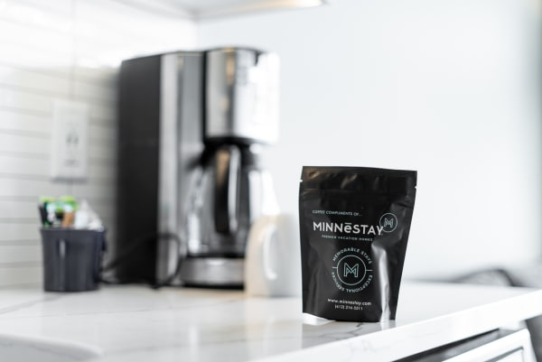 A coffee packet labeled MINNESTAY on a kitchen counter with a coffee maker in the background.