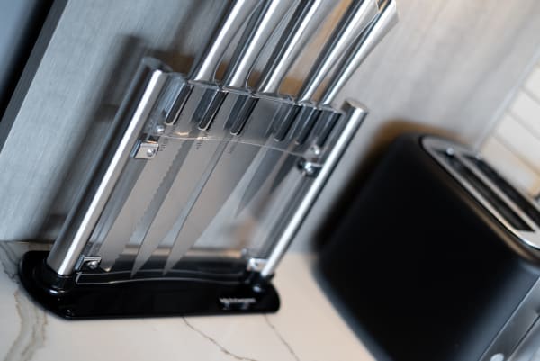 Knife block set featuring various stainless steel knives on a marble countertop.