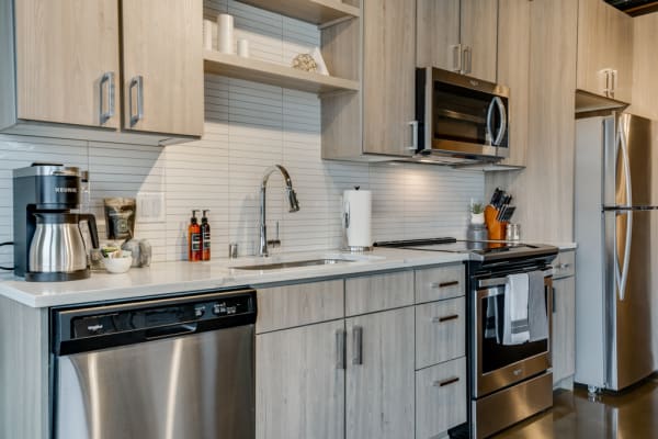 Modern kitchen featuring light wood cabinets, stainless steel appliances, and a Keurig coffee maker.