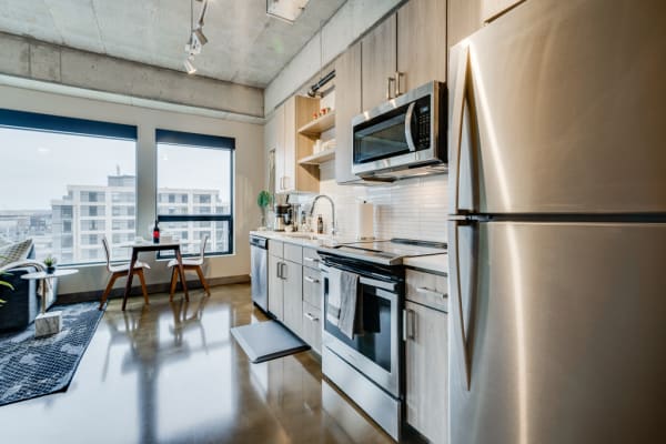 A contemporary kitchen with stainless appliances and a small dining area by the window.