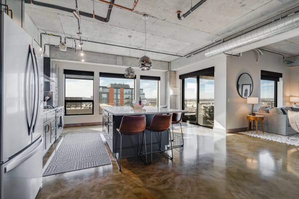 Modern apartment interior with open kitchen and living space, featuring city views.