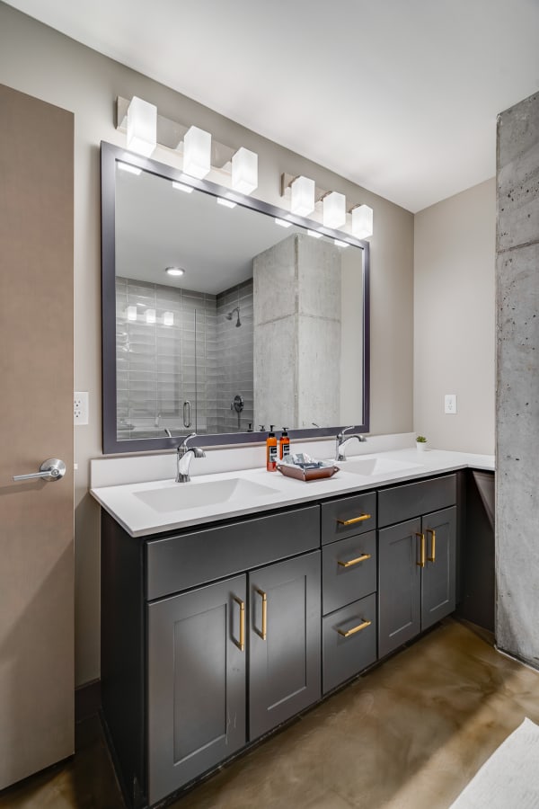 Modern bathroom featuring a double vanity with a dark cabinet, white countertop, and illuminated mirror.