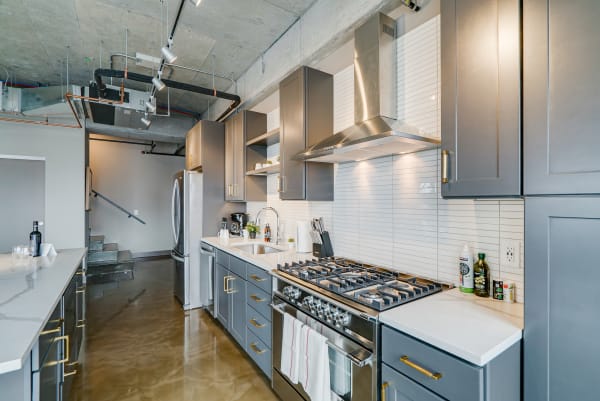 Contemporary kitchen with gray cabinets, stainless steel stove, and polished concrete floors.
