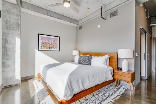 Modern bedroom with wooden bed, patterned throw pillow, and a city skyline picture on the wall.