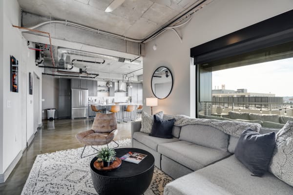 Modern living room with a gray sectional sofa, black coffee table, and open kitchen