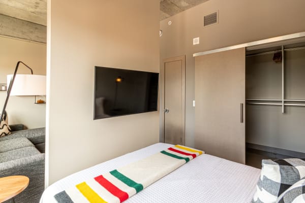 Modern bedroom with a bed, colorful blanket, TV, and sliding closet doors.