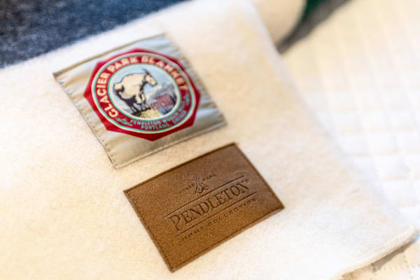 Diverse patches on a Pendleton blanket featuring Glacier Park design and leather logo.