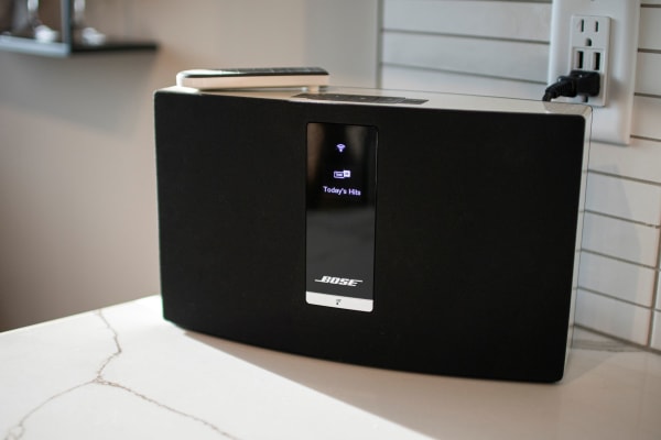 Bose speaker on a marble countertop showing a digital display of music streaming.