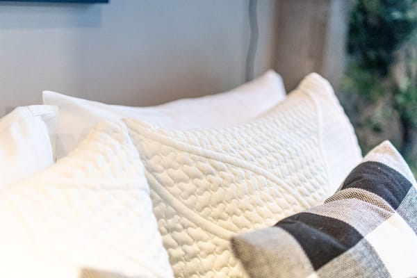 Decorative white and checkered pillows arranged on a sofa.