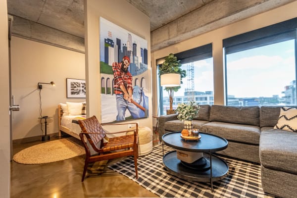 A cozy living room with a sectional sofa, a coffee table, and a colorful mural on the wall.