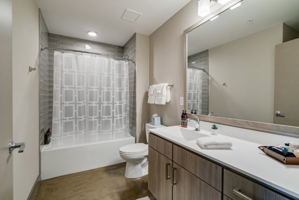 A modern bathroom with a bathtub, stylish vanity, and toiletries on the countertop.