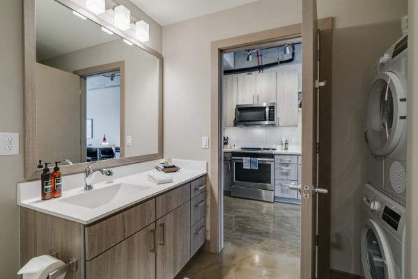 Modern bathroom opening to a kitchen area with laundry facilities.