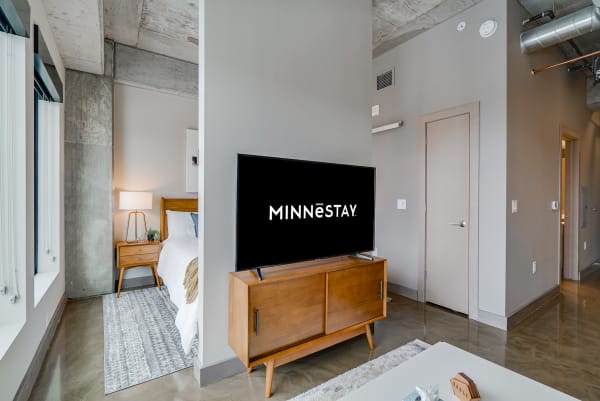 Interior view of a modern studio apartment with living area and bed visible.