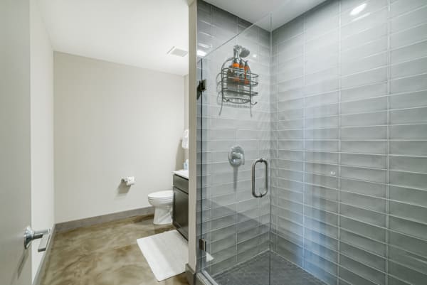 Modern bathroom with glass shower, toilet, and dark cabinet.