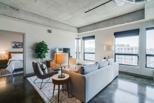A cozy modern living room featuring a grey sectional sofa, a wooden coffee table, and an inviting reading nook with an armchair.