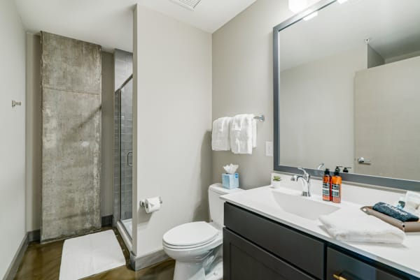Contemporary bathroom featuring a glass shower, concrete wall, and minimalistic decor.