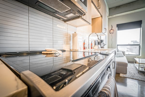A contemporary kitchen featuring a black cooktop, white tiled backsplash, and modern wooden cabinetry.