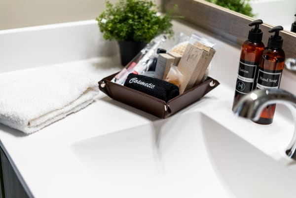 Bathroom countertop with a towel, cosmetic items in a tray, and lotion and hand soap bottles.