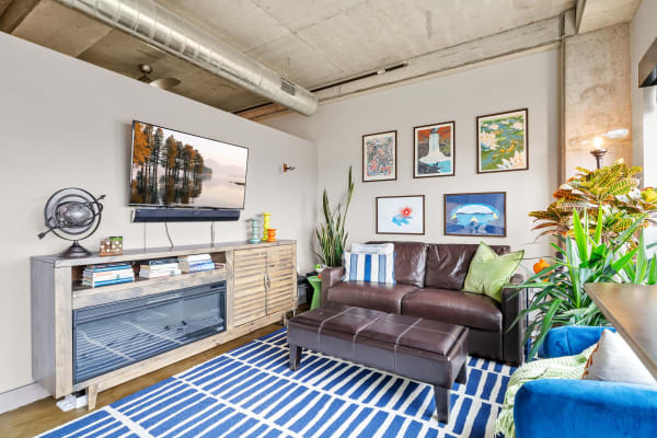 A contemporary living room with a brown leather sofa, colorful accents, and framed artworks on the wall.