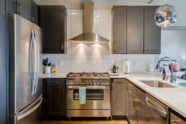 Modern kitchen featuring gray cabinets, a stainless steel range, and polished countertops.