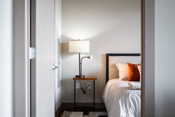Interior view of a modern bedroom with a bed and a bedside lamp.